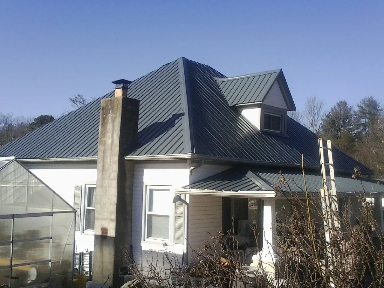 Dark blue standing seam metal roof on a white farmhouse with dormer — Slate & Tile Roof Repair by Roofing Brothers in National Park
