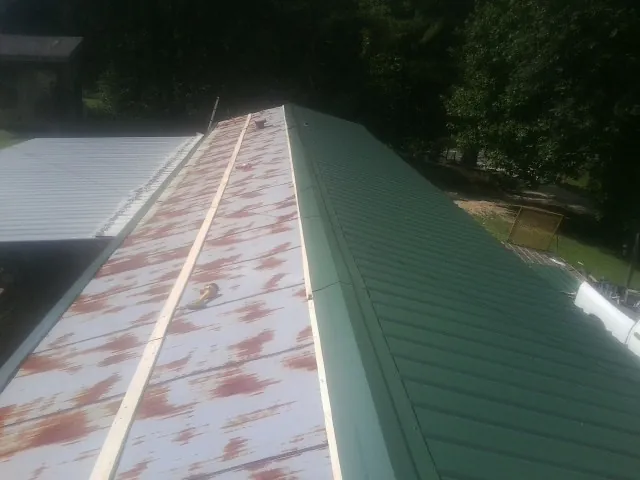 Old rusted panels beside newly installed green metal roofing — Wind Damage Roof Repair by Roofing Brothers in National Park
