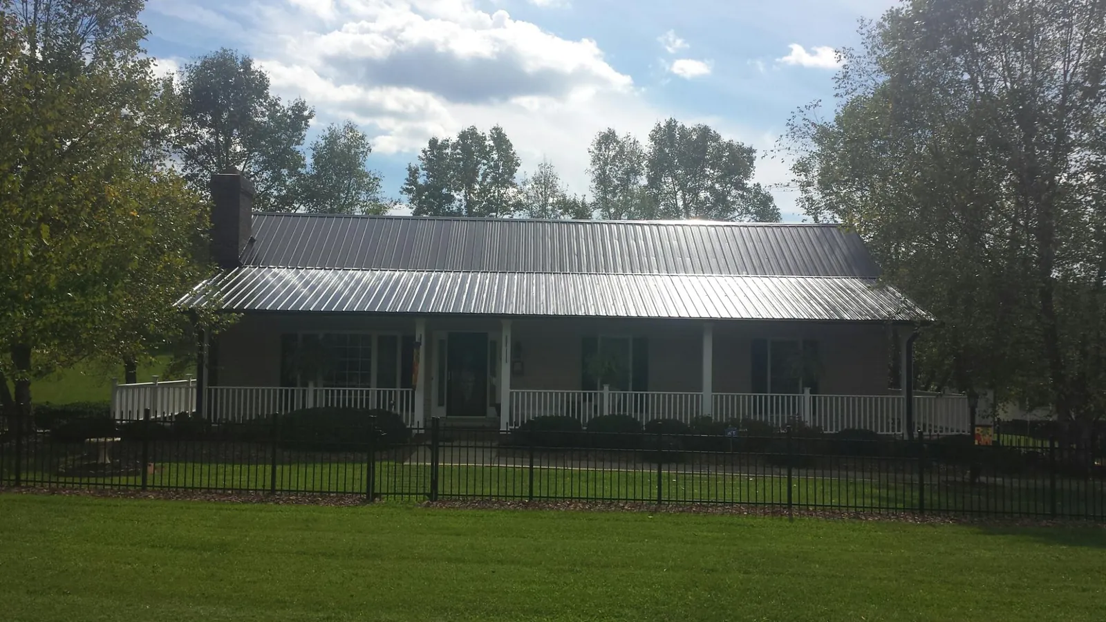 Gray metal roof on a brick ranch with a full width front porch — Gutter Guard Installation work by our crew in National Park