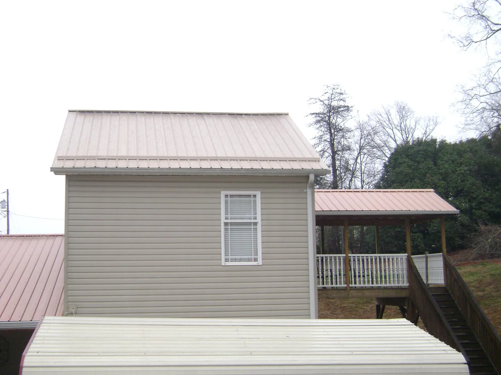Tan metal roofs on a two story addition and attached porch, from a Roof Replacement job in National Park